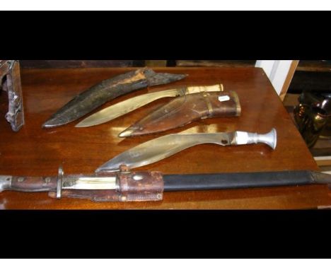 An antique kukri in leather scabbard, together with a sword bayonet and one other kukri CONDITION REPORTWhite metal handle - 