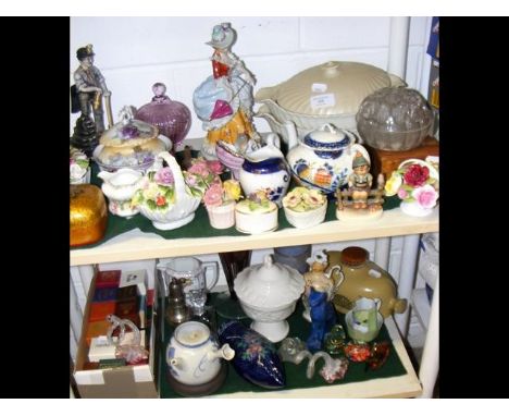 Two shelves of collectable ceramic and glassware including foot warmer figurine