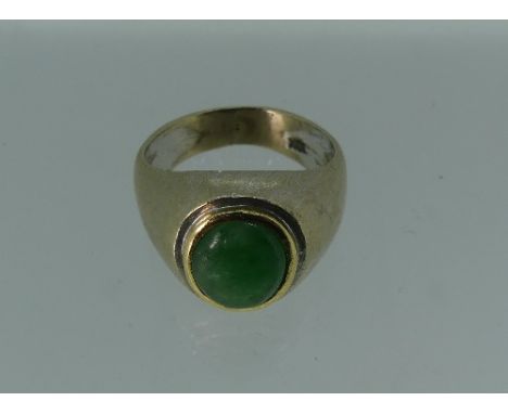 An 18k white gold Ring, the centre set with an oval cabochon jade, within a yellow gold border, Size H½.