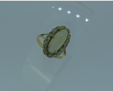 A opal and diamond Ring, the narrow oval opal surrounded by sixteen small diamonds, the whole in yellow gold marked 750, shan