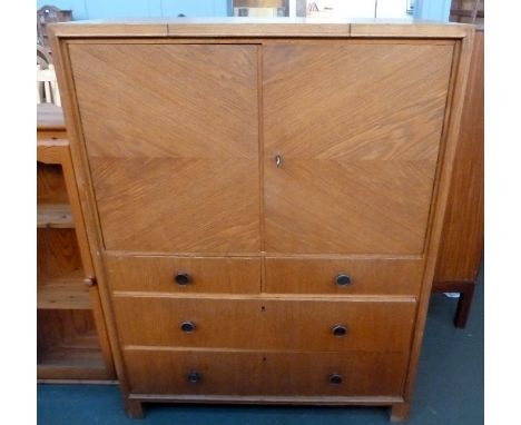 A mid century oak dressing cupboard, one cupboard door with internal shelf over two short drawers over two long, retractable 