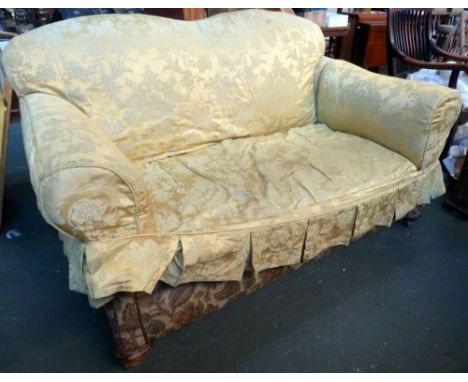 A Victorian drop end sofa with loose yellow covers and bun feet on casters