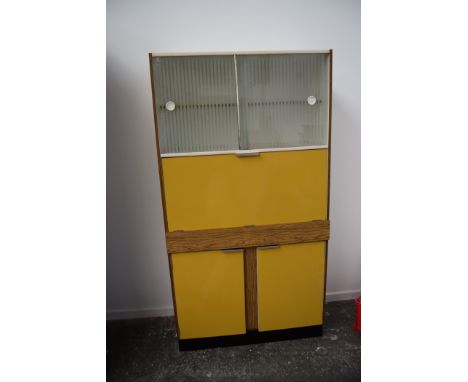 A vintage 1970s kitchen unit highlighted in yellow with cutlery drawer