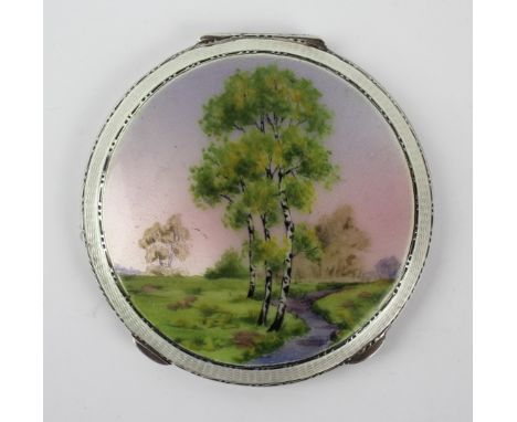 A George VI hallmarked silver and guilloche enamel powder compact
Of circular form, decorated with trees in landscape scene, 
