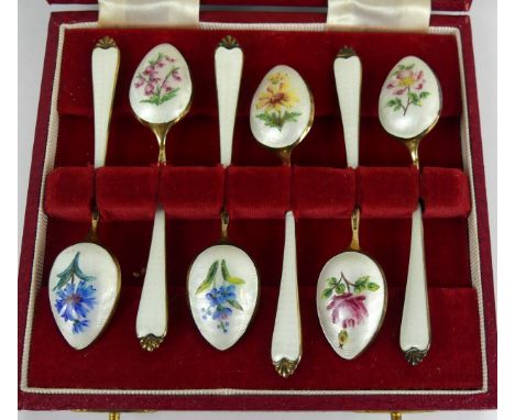 A cased set of mid 20th Century silver and enamel teaspoons Each designed as a silver gilt teaspoon with white guilloche stem