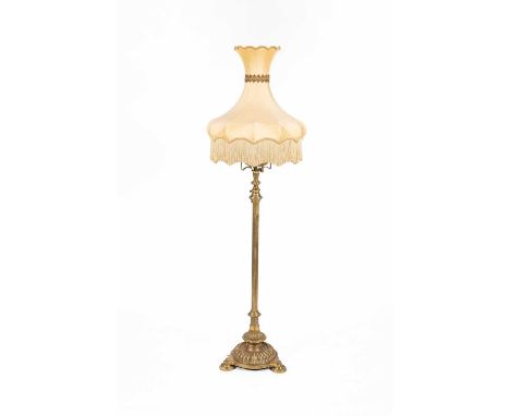 A Victorian brass standard oil lamp with extending shaft, fluted column, reservoir and base on three turned feet, with shade,