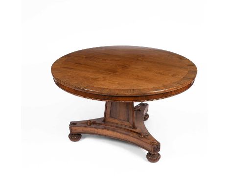 A Regency rosewood and crossbanded centre table, the circular tip-up top on a panelled triangular column to a triform base on