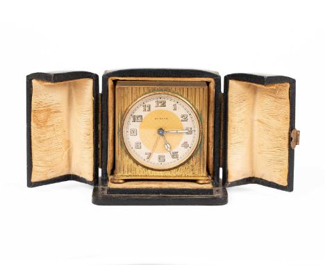 A small Zenith travelling alarm clock, the dial with arabic numerals, the case with reeded decoration on compressed bun feet,