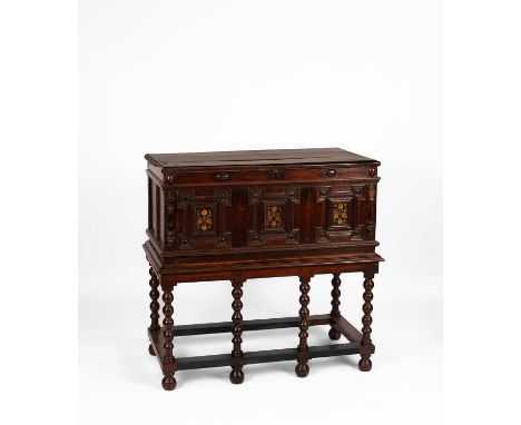 An oak coffer on later stand, the three-panel hinged top above a cabochon carved frieze and triple panel front with floral ca