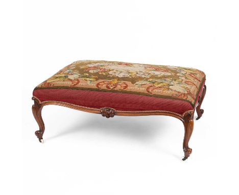 A Victorian carved walnut framed stool with needlework upholstered top on cabriole legs, the knurled feet on white ceramic ca