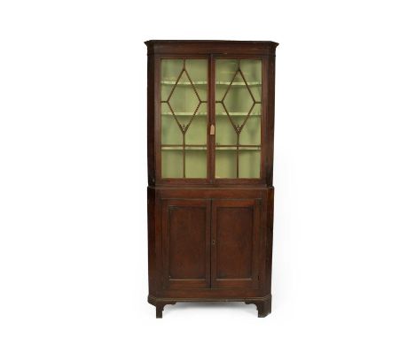 A George III mahogany floor standing corner cupboard, the moulded cornice above twin astragal glazed doors enclosing a painte