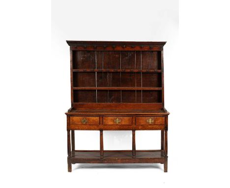 A late 18th/early 19th Century oak dresser, the upper section with a moulded cornice above shelves, the base with three short