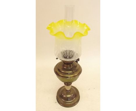 A Victorian oil lamp with yellow tinted glass shade