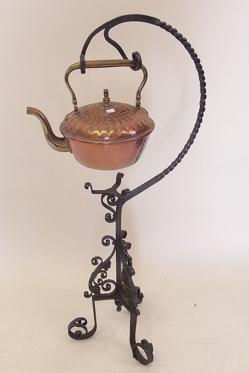 A copper kettle suspended on wrought iron stand