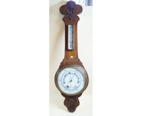 An Edwardian oak cased aneroid barometer/thermometer with carved decoration