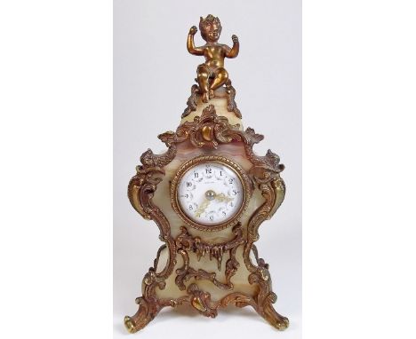 A 19th century small Tiffany onyx and ormolu mounted mantel clock with child seated to top and rococo scrollwork decoration, 