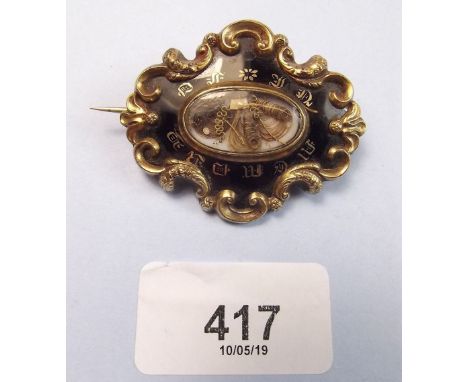 A Victorian yellow metal and black enamel mourning brooch with hair panel