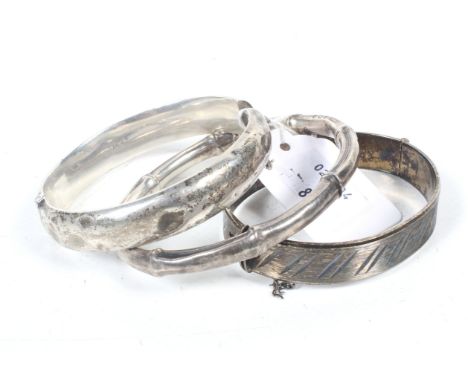 Three silver bangles including a slave bangle resembling bamboo. Hallmarks for Birmingham 1912; a part foliate engraved hollo