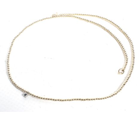 A Continental yellow metal bead necklace with a central small round brilliant diamond single stone drop. The beads strung on 