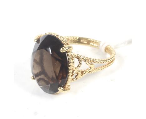 A vintage Italian gold and oval smokey quartz single stone ring. The oval mixed-cut stone claw set on a pierced rope-twist ga