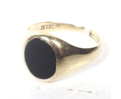 A vintage 9ct gold and black oynx oval signet ring. THe oval black onyx panel rub-over set between tapering shoulders on a D-