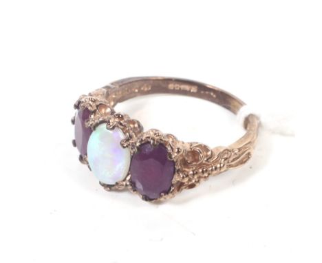 A modern 9ct rose gold, opal and ruby three stone ring in Victorian style. Centred with an oval cabochon white opal between o