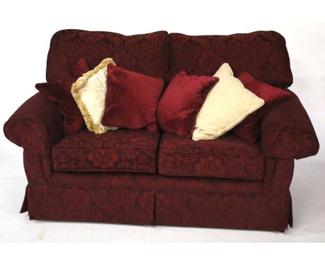 A two-seater maroon sofa with extra cushions. Circa H100cm x W170cm x D90cm