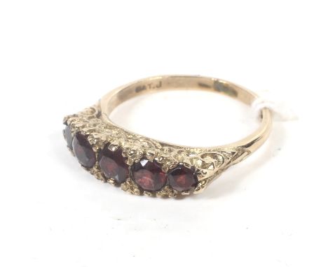 A vintage 9ct gold and garnet five stone half-hoop ring. The cast scroll gallery on a D-section shank with indistinct hallmar