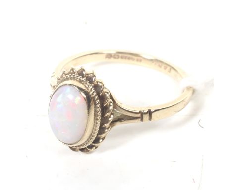 A vintage 9ct gold and opal single stone ring. The oval cabochon white opal rub-over set within a rope-twist surround on a D-