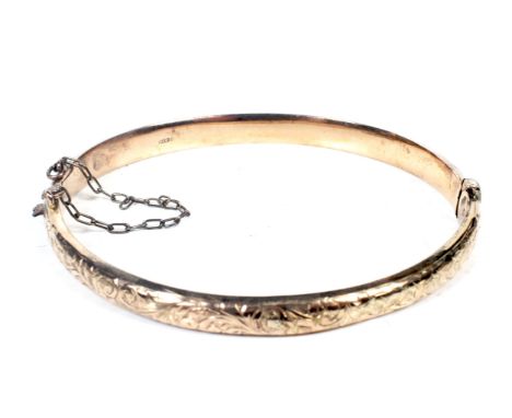 An Edwardian 9ct rose gold hollow hinged bangle. The part foliate engraved domed hoop with hallmarks for Birmingham 1909, 6gW