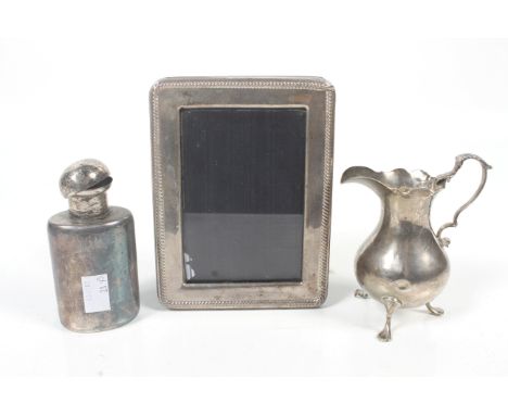 A silver cream jug, flask and photograph frame. Comprising; an early George III silver baluster shaped cream jug with a leaf-