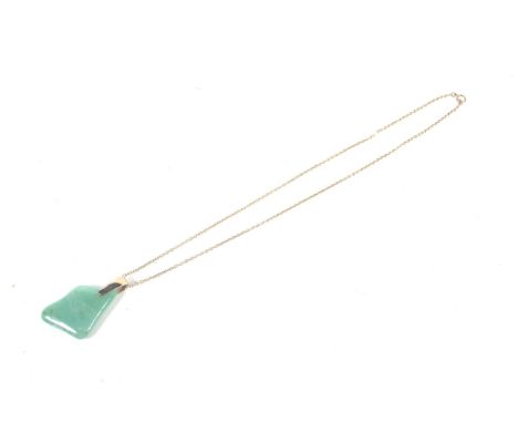 A mid 20th century gold and green chalcedony pendant, on a gold chain. The abstract stone of vaguely triangular outline, with