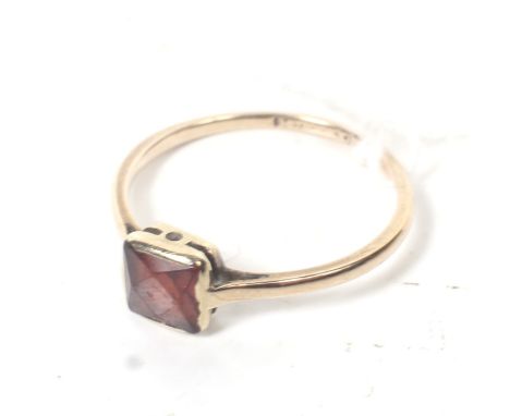 An early 20th century rose gold and square garnet single stone ring. The stone in a partial rub-over mount on a D-section sha