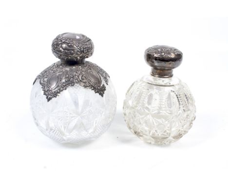 Two silver mounted clear cut-glass scent bottles. One with a pierced and shaped collar and hinged lid profusely embossed with