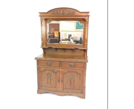 A Victorian oak mirrorback sideboard, the pediment carved with a scrolling Art Nouveau motif, raised on fluted columns, termi