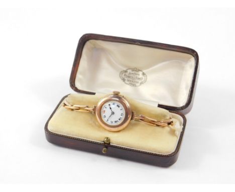An early 20thC 9ct gold circular cased lady's wristwatch, white enamel dial bearing Roman numerals on a gold plated strap, bo