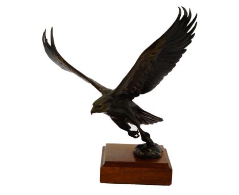 A bronze sculpture of a Golden Eagle, cast in flight exiting the water with a fish, signed Constock, raised on a wooden plint