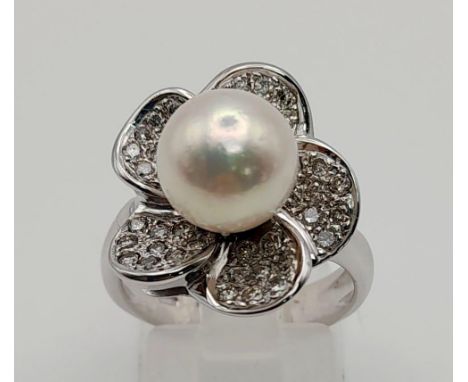 An attractive 18 K white gold ring with a diamond studded flower on top and a genuine round white pearl (9 mm) at centre. rin