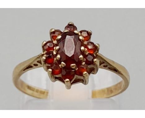 A 9K Yellow Gold Garnet Ring. Central garnet stone surrounded by a ring of smaller garnets. Size K. 1.6g 