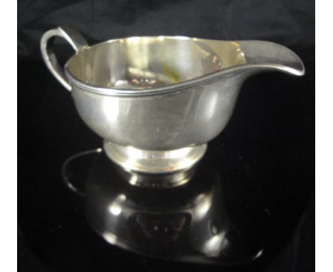 A modern silver sauceboat in the Art Deco manner, the plain body with reeded edge, raised on a plain circular stepped foot (b