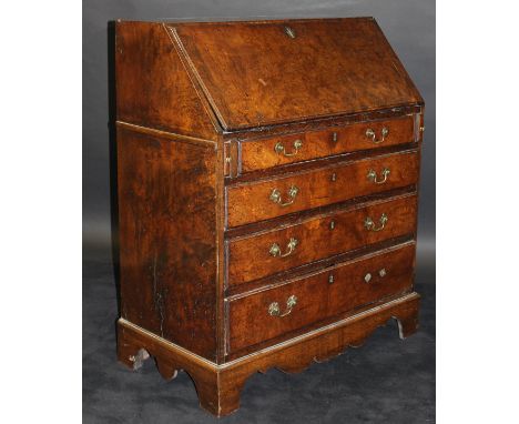 An 18th Century burr brown oak bureau, the single piece top over a sloping fall enclosing a fitted interior with central deed