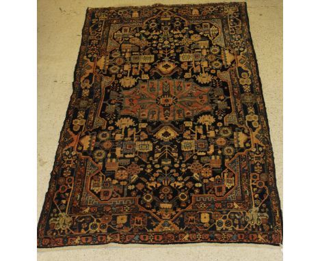 A Caucasian carpet, the central panel set with central medallion on a dark blue ground with stylised floral motifs, within a 