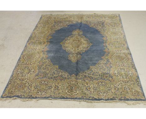 A Persian carpet, the central panel set with floral decorated medallion on a plain blue ground with floral decorated corners 