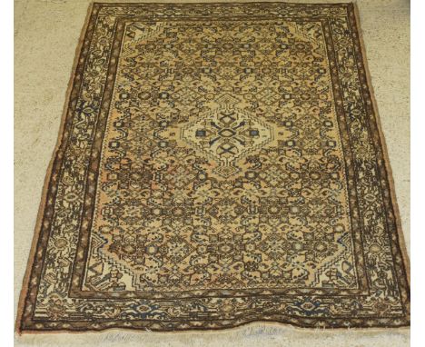 A Persian carpet, the central panel set with lozenge shaped medallion on a pink ground with repeating geometric design, withi