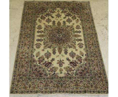 A Persian carpet, the central panel set with a stylised floral decorated starburst medallion on a cream ground with hook and 