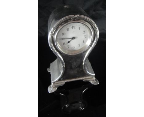 A George V silver cased mantle clock of small proportions with ribbon, reeded and cross decoration, the white enamel dial set