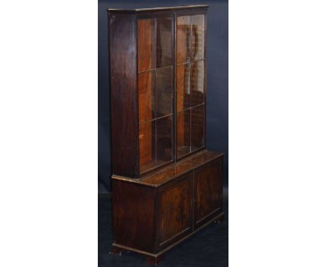 A Victorian mahogany bookcase cabinet, the upper section with glazed and barred doors enclosing two banks of adjustable shelv