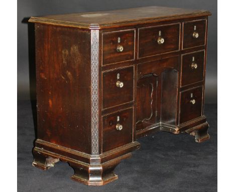 An early 19th Century mahogany kneehole desk / dressing table of small proportions, the plain top with moulded edge over a ce