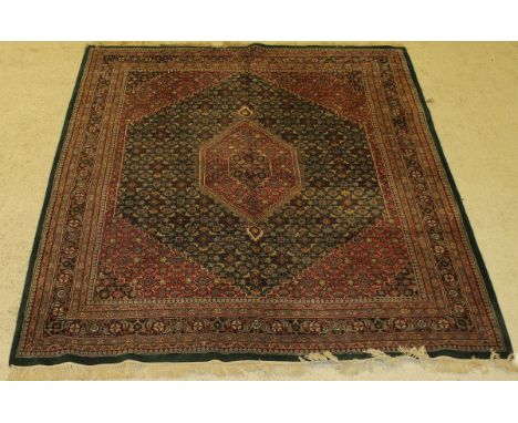 An Oriental carpet, the central panel set with lozenge shaped medallion on a green ground with stylised floral motifs, within