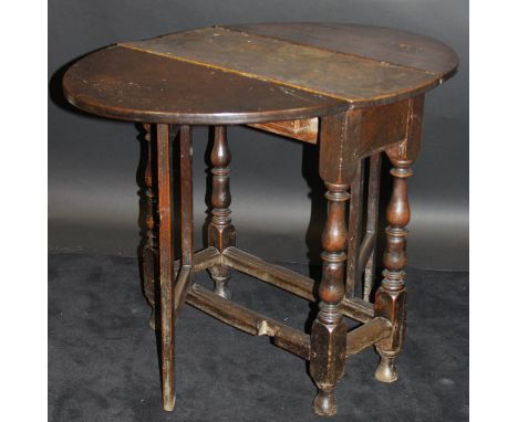 An 18th Century oak oval gate-leg drop-leaf tea table, raised on turned and ringed supports to blocks united by stretchers, 9